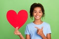 Photo of young school afro girl teen smile point finger paper heart card valentine day choice promo  over green Royalty Free Stock Photo