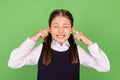 Photo of young school girl unhappy negative close cover ears annoyed loud over green color background