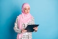 Photo of young serious arabian woman look read clipboard check plan wear hijab isolated over blue color background