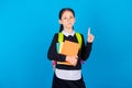 Photo of young serious schoolgirl point finger smart wear glasses hold textbook isolated on blue color background