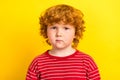 Photo of young serious small charming redhead boy wear striped sweater isolated on shine yellow color background