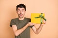 Photo of young shocked amazed surprised man showing demonstrating unexpected present isolated on beige color background