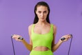 Photo of young slim woman doing exercise with jump rope and looking at camera Royalty Free Stock Photo