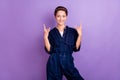 Photo of young smiling brutal harsh hipster woman showing rock'n'roll sign gesture isolated on purple color background Royalty Free Stock Photo