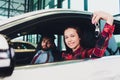 Photo of young smiling mixed race woman sitting inside her new car and holding key. Concept for car rental. Royalty Free Stock Photo