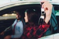 Photo of young smiling mixed race woman sitting inside her new car and holding key. Concept for car rental. Royalty Free Stock Photo