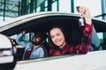 Photo of young smiling mixed race woman sitting inside her new car and holding key. Concept for car rental. Royalty Free Stock Photo