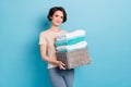 Photo of young stunning lady working at cleaning service hold pile of washed clothes isolated on blue color background