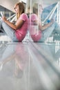 Portrait of young teenage girl sitting on the floor and using digital tablet while waiting for her flight in airport Royalty Free Stock Photo