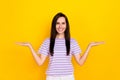 Photo of young toothy smiling lady hold two objects compare price quality which better  on yellow color Royalty Free Stock Photo