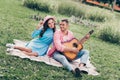 Photo of young two students couple lovers sitting grass in park guy playing music guitar instrumental Royalty Free Stock Photo