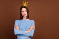 Photo of young unhappy moody girl folded hands wear crown princess look empty space isolated over brown color background