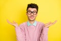 Photo of young unhappy upset uncertain unsure man in glasses shrug shoulders isolated on yellow color background