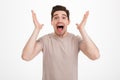 Photo of young unshaved guy with exciting facial expressions shouting and gesturing with hands in happiness and