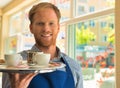 Young waiter serving coffee and cookies at restaurant Royalty Free Stock Photo