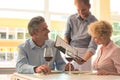 Young waiter showing menu to mature couple at restaurant