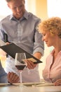 Young waiter showing menu to mature couple at restaurant