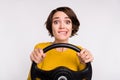Photo of young woman bite lips teeth worried hold steering-wheel driver fast speed isolated over grey color background
