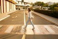 Photo of young woman crossing street and holding cup of coffee to go Royalty Free Stock Photo