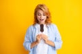 Photo of young woman eats delicious ice cream, enjoys frozen dessert, dressed in casual clothes, isolated on yellow Royalty Free Stock Photo