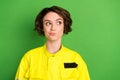 Photo of young woman firefighter hesitate doubt think look empty space isolated over green color background