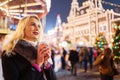 Photo of young woman with glass of coffee in hands in park on background of carousel Royalty Free Stock Photo