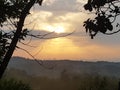 Photograph of a blazing nuanced sky during a sunset above the contrast of a countryside landscape