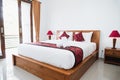 Photograph of bright white bedroom with wooden bed