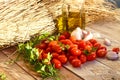 Photograph of Cherry tomatoes with garlics and olive oil on rustic background.