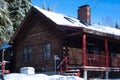 Rustic Red Log Cabin Covered in Snow, Ice and Icicles During Winter