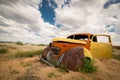 A photograph of a colourful red and yellow abandoned vintage car wreck