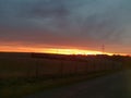 Photograph of a countryside landscape against a blazing cloudy summer sky during dusk