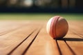 photograph of a cricket players ball rests on wooden basketball court