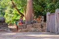 Photograph depicting a young Khmer girl seated on old stone blocks, engaged in selling