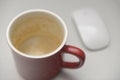 Empty red coffee mug with espresso residue on white desk and blurred wireless computer mouse minimal office workspace scene Royalty Free Stock Photo