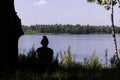 Silhouette of Solitude: Person Contemplating by a Forest Lake