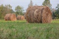 Photograph of a field with rolls of hay that will be food for farm animals