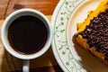 Photograph of full cup of coffee with a piece of cake covered in chocolate. Royalty Free Stock Photo