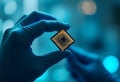 Photograph of gloved hand holding a small golden grid-patterned microchip blue bokeh background soft lighting Royalty Free Stock Photo