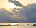 Bright Golden Yellow Sun behind Dark Grey Clouds with Warm Colors in Sky and Reflection in Still Sea Water - Neil Island, Andaman Royalty Free Stock Photo