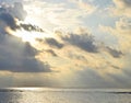 Bright Sunbeams from Golden Yellow Sun Behind Dark Clouds and Spreading over Still Sea Water - Descent of Divine Blessings Royalty Free Stock Photo