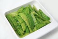 Green cooked stir-fried vegetable snow peas bean on square rectangular plate white background