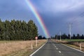 Photograph of a large rainbow over a regional road in New Zealand