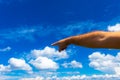 Photograph of a man`s hand pointing in one direction, against a background of blue sky with white summer clouds; copy space Royalty Free Stock Photo