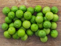 Green lemons on wooden board