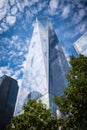 One World Trade Center enveloped and reflecting white fluffy clouds in the blue sky