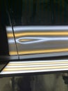 A paintless dent repair light showing a large crease on a door of a car