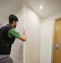 professional putting putty with his spatula to plasterboard wall, inside apartment. copy space Royalty Free Stock Photo