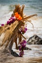 Purple flower lei with an orange bow hanging on a stump at the ocean`s edge Royalty Free Stock Photo