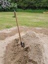 A photograph of a shovel in a pile of construction sand